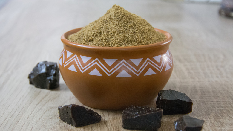 A jar of asafoetida on a table next to some blocks of resin