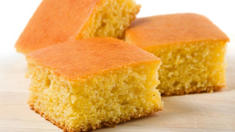 Three squares of cornbread on a wooden surface