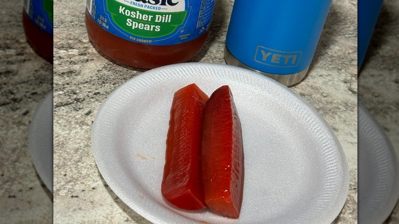A close up of two Kool-Aid pickles on a white plate