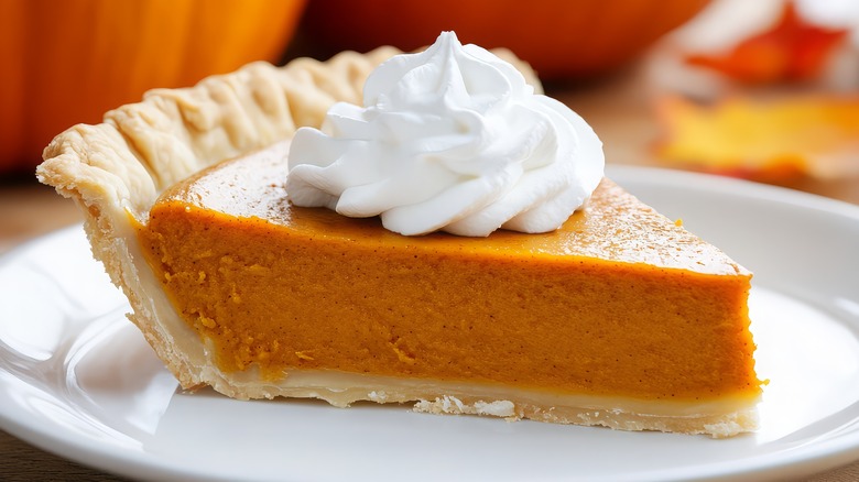 A slice of pumpkin pie, topped with whipped cream