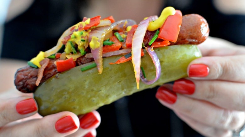 Close-up of someone holding a pickle hot dog
