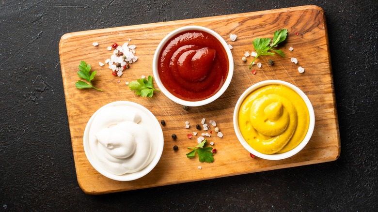 ketchup, mustard, and mayo ramekins on board