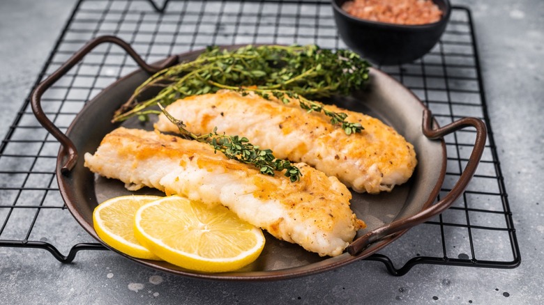 cod on a skillet with herbs and lemon