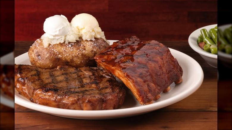 small rack of ribs on a plate with steak and potato