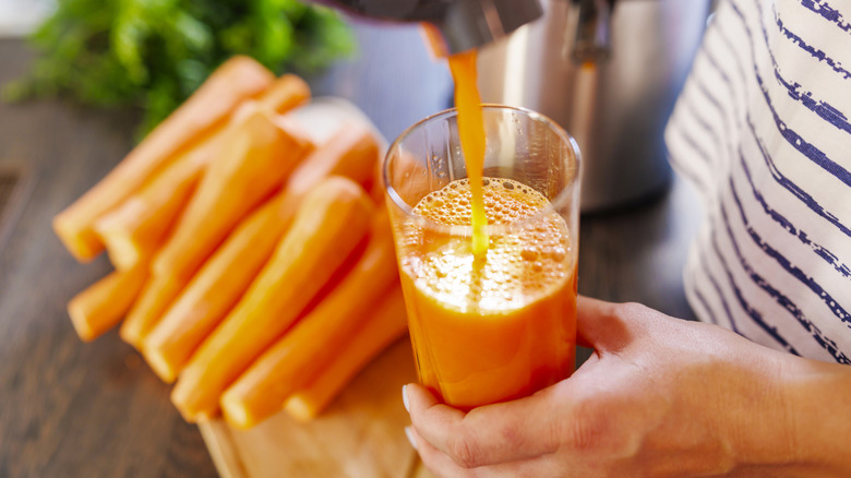 Pouring rfesh carrot juice into a glass