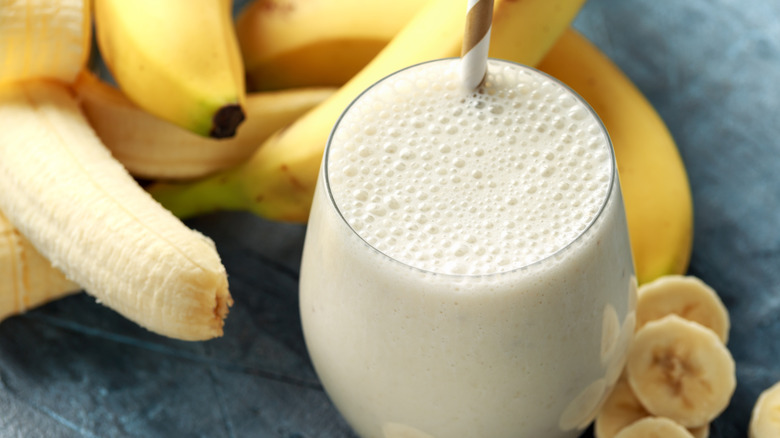 Bananas alongside glass containing smoothie beverage