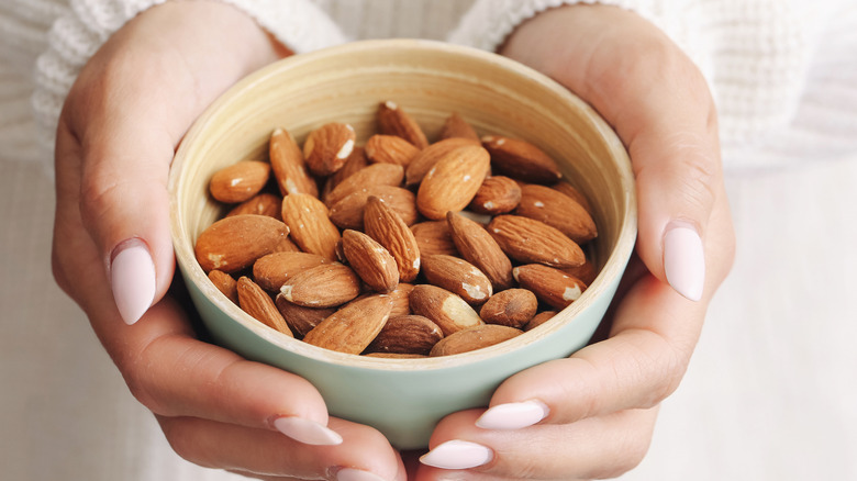 Hands holding a bowl of almonds