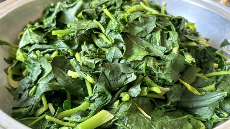 pan of green cooked spinach with stems