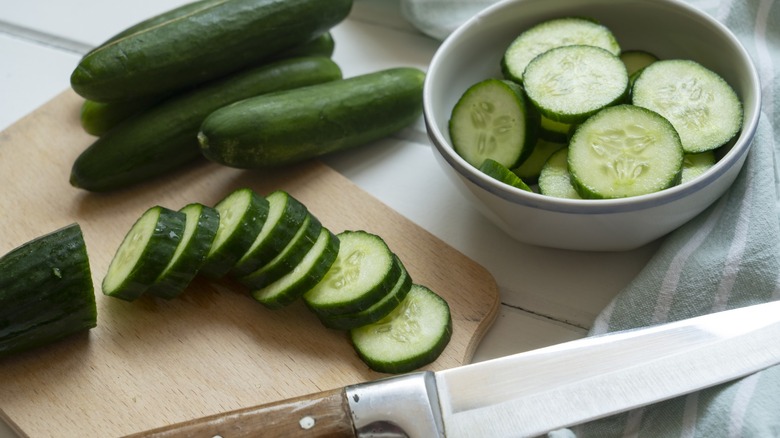 sliced cucumbers with cutting board and bowl