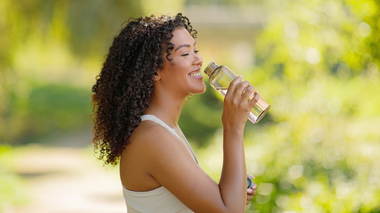 young woman drinks from a reusable bottle of water