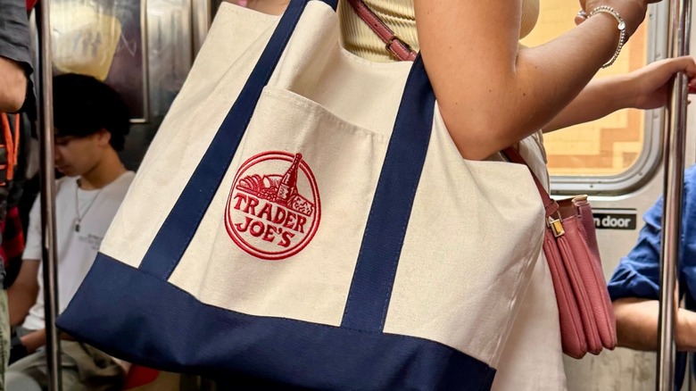 woman on subway carries trader joe's tote on shoulder