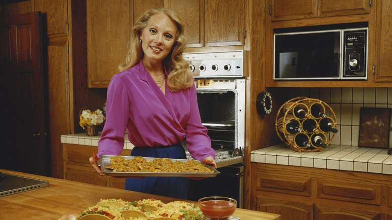 home cook holds pan in 80s kitchen