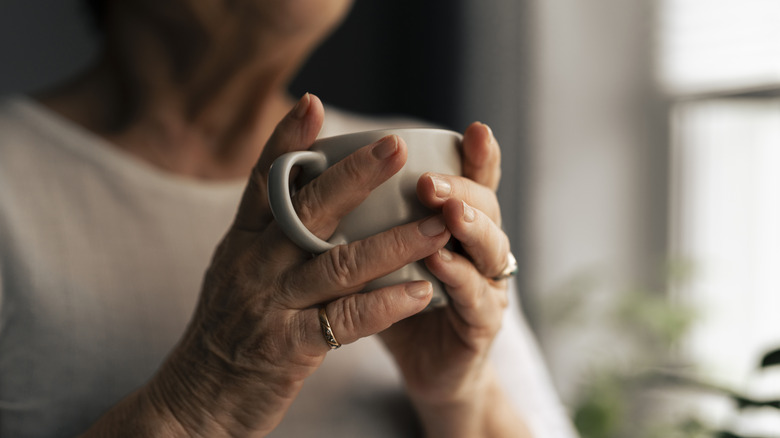 Closeup person holding white mug in both hands