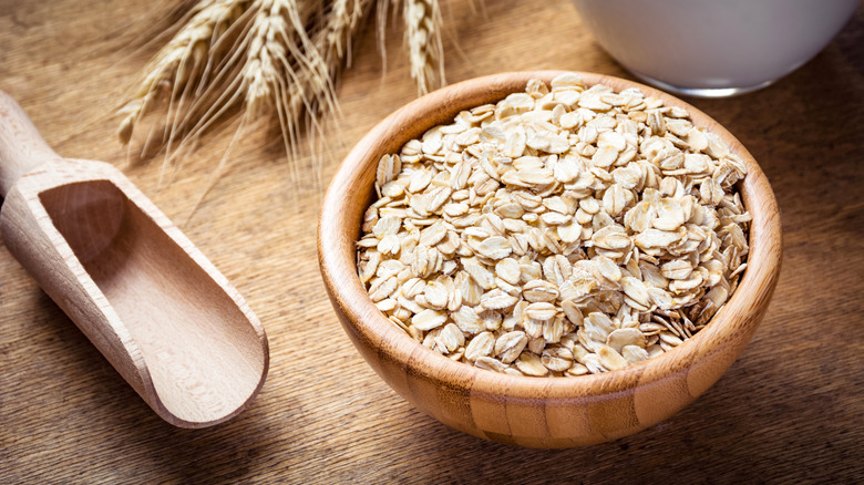 Rolled oats, milk and wheat ears on wooden background