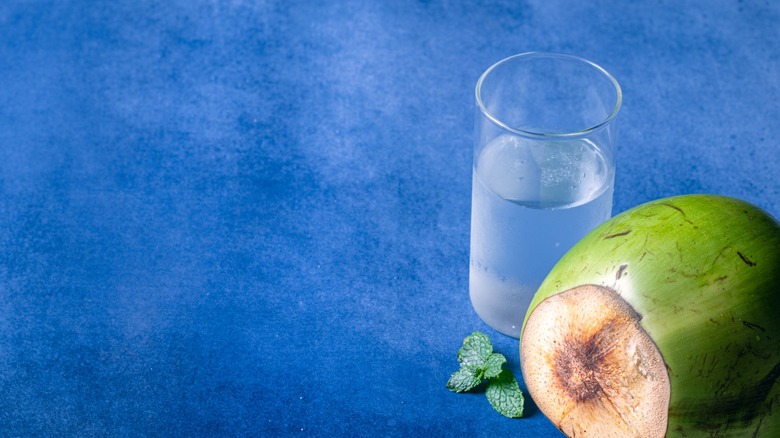 green coconut with glass of coconut water
