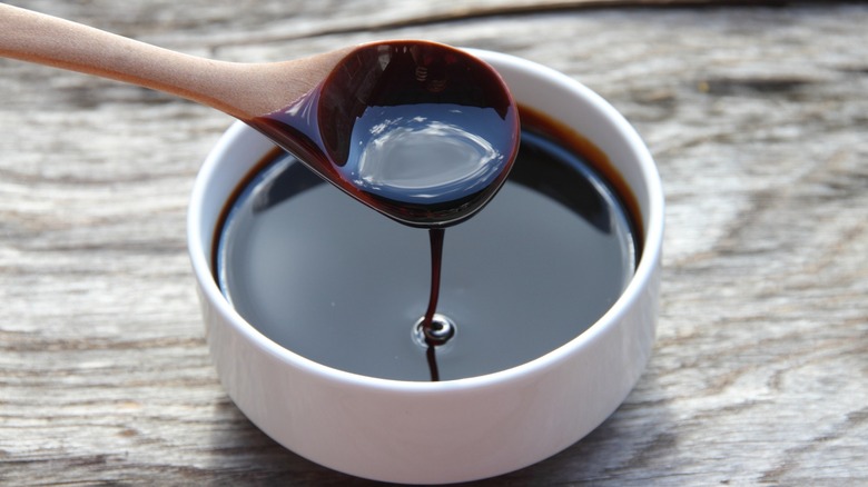molasses drips from a spoon over ramekin