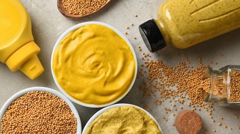 varieties of prepared and raw mustard on off-white surface