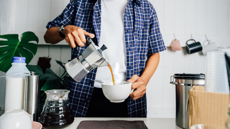 Man pouring coffee from Moka pot. 