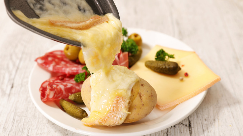 raclette cheese being poured on a potato