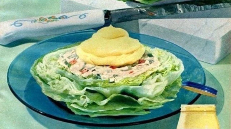 Plate with half head of lettuce filled with salad and garnished with mayonnaise