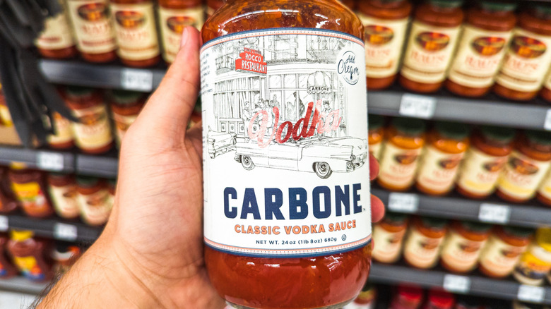 Someone holding a jar of Carbone classic vodka sauce