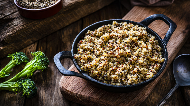 Cooked quinoa in a cast iron pan on a rustic wooden table