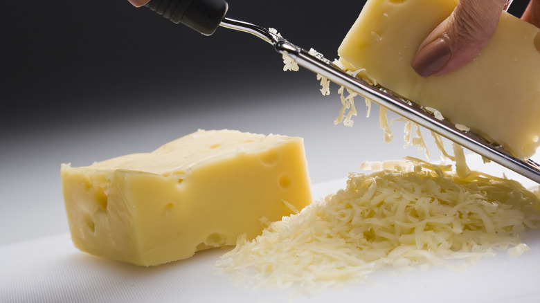 grating cheese onto cutting board