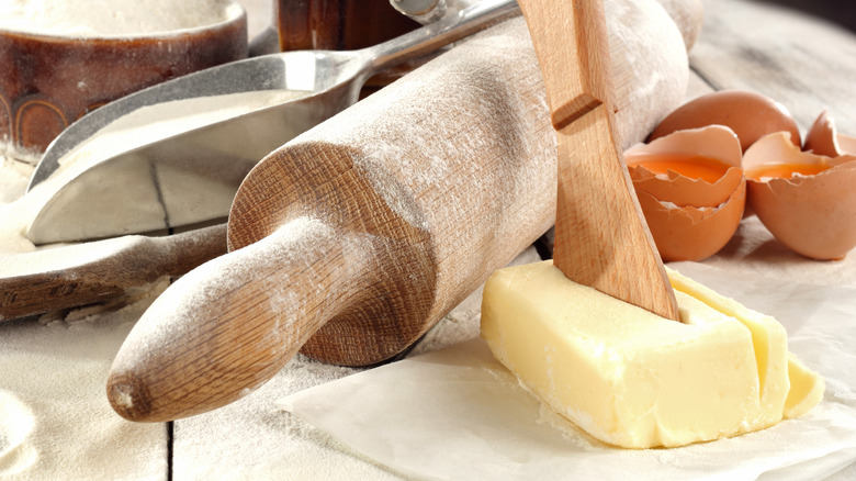 Block of butter next to a wooden rolling pin