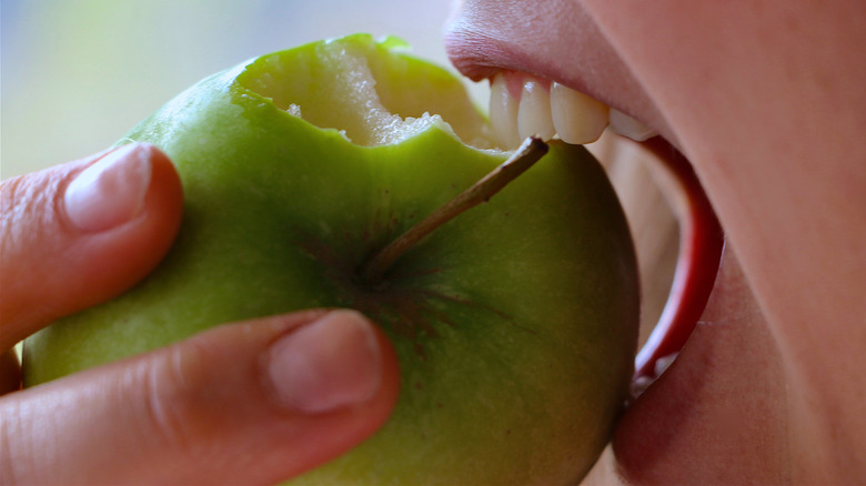 closeup shot of woman biting into green apple