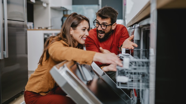 Couple enjoying a debate about loading the dishwasher