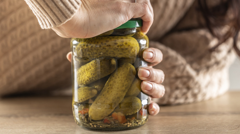 Woman opening a jar of pickles