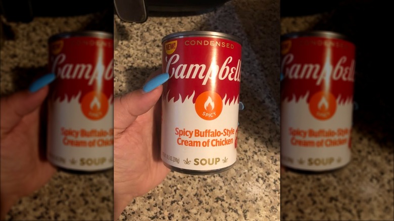 hand with blue nails holds can of campbell's buffalo soup