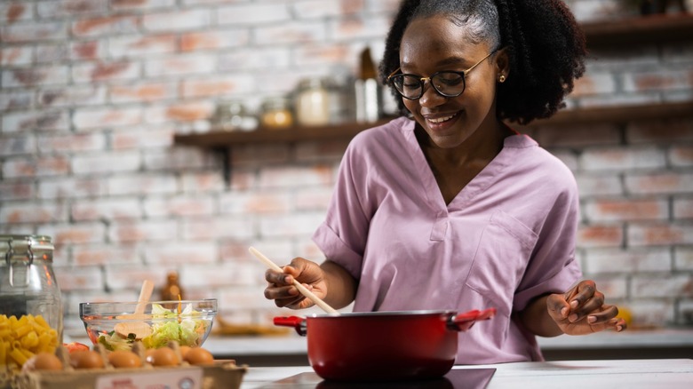 young woman cooks pasta in kitchen