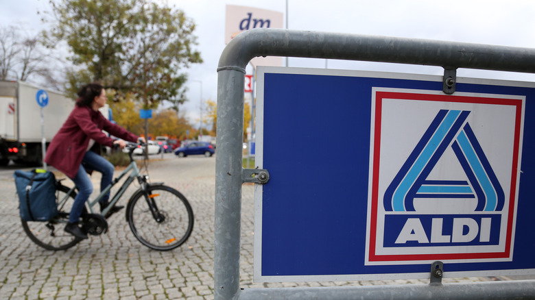 person on bicycle rides past aldi cart corral