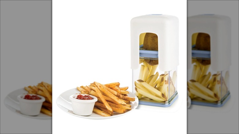 Plastic fry chopper with a whole potato and cut potatoes inside, next to a plate of cooked fries with ketchup
