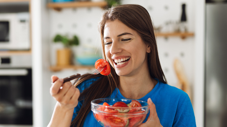 Woman eating sliced tomatoes from a bowl