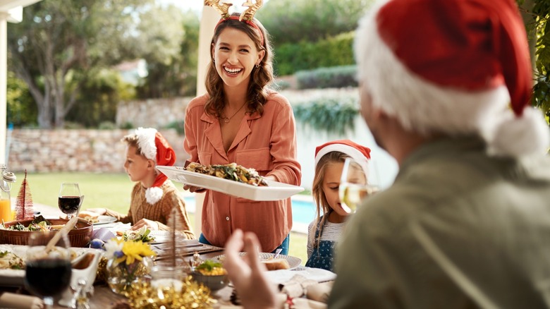a woman carries food to a holiday table