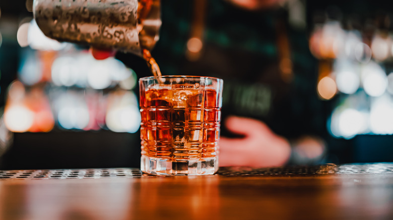 person pouring negroni from cocktail shaker