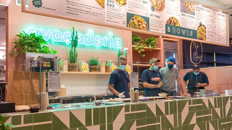 Masked workers serve food at Avo
