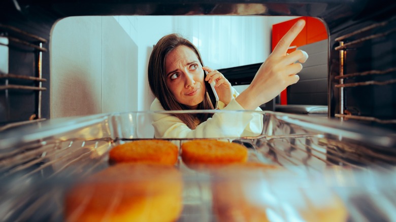 woman on phone grimaces at broken stove