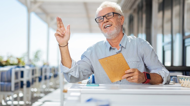 elderly man beckons server at restaurant