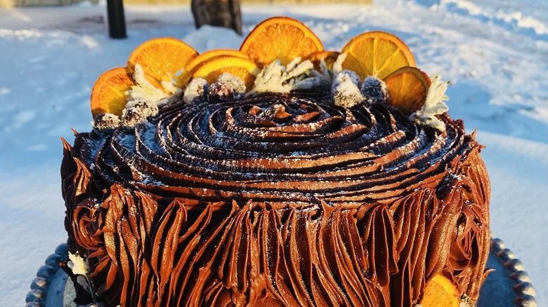 Iced chocolate cake dusted with icing sugar and garnished with orange slices