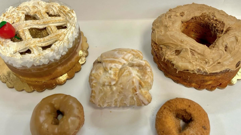 Large white pastry box with two iced cakes, two donuts, and a dumpling