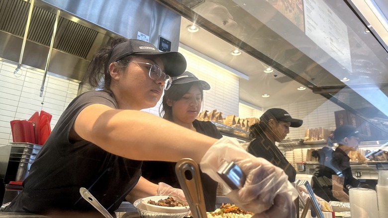 chipotle employees prepare customer food