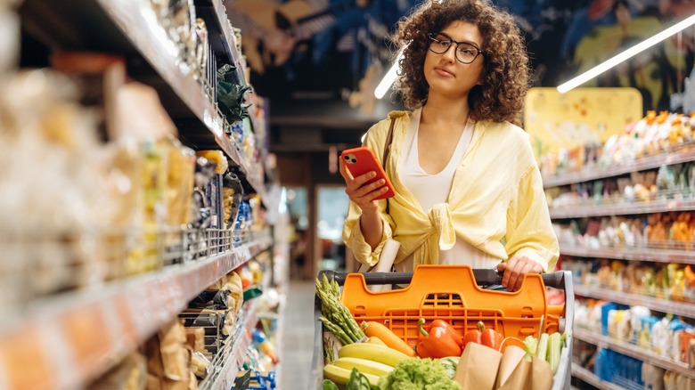woman shops at grocery store with smartphone