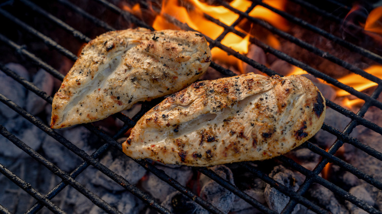 seasoned chicken breasts on fiery grill