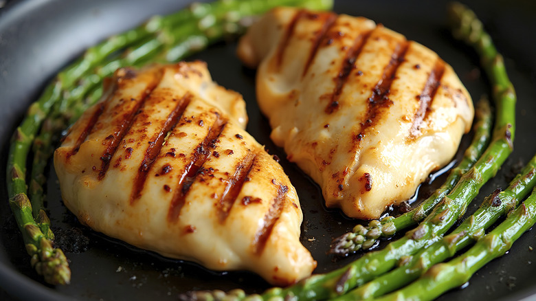 grilled chicken breasts in pan with asparagus