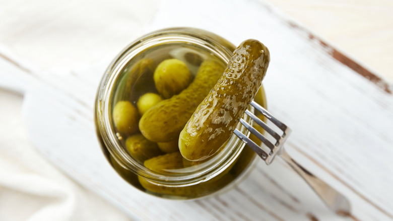 Above view of pickles in jar with fork