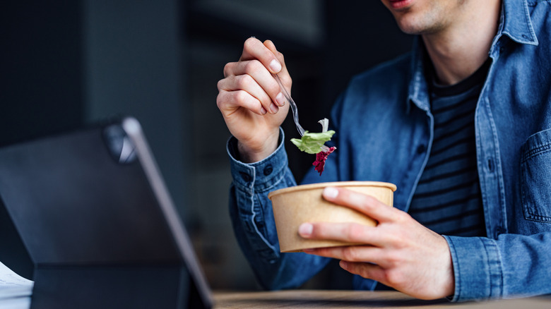 A man eating salad for lunch while on a video call