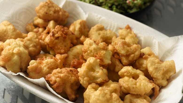 deep fried cauliflower florets on paper napkins in dish